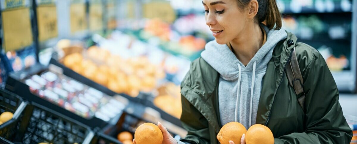 fiatal lány narancsot vásárol a szupermarketben