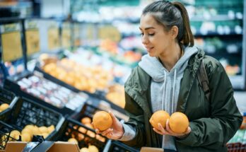 fiatal lány narancsot vásárol a szupermarketben