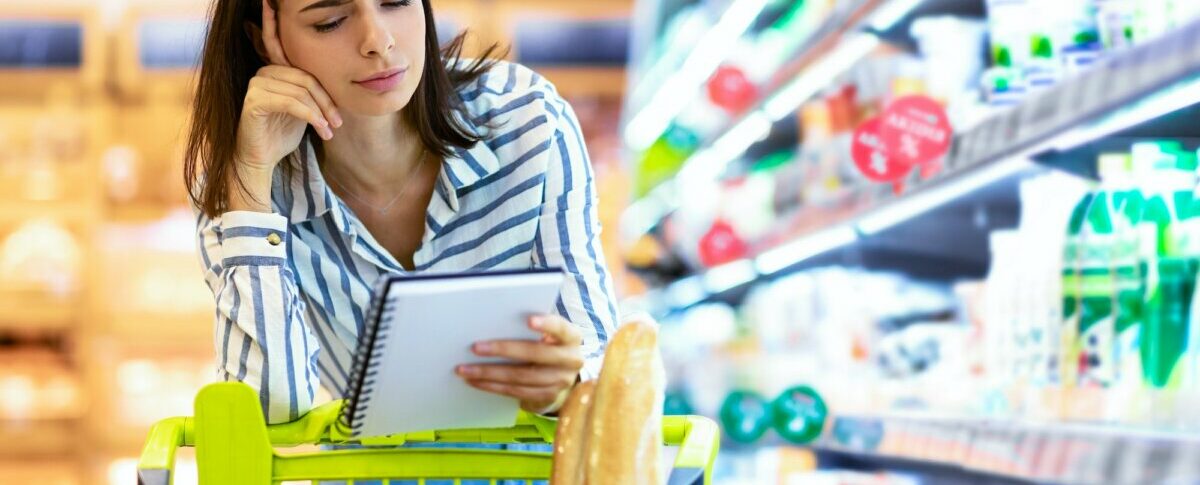 fiatal nő olvassa a bevásárlólistát a supermarketben